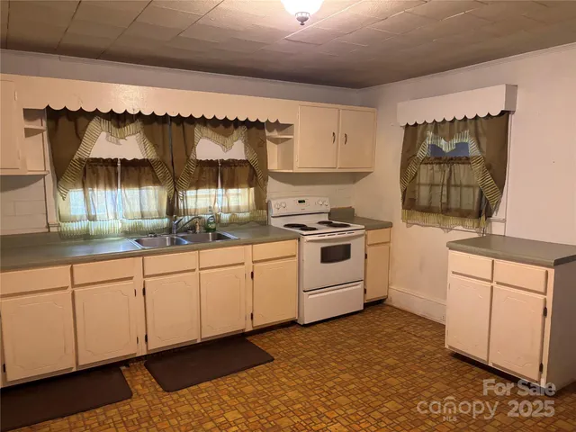a kitchen with granite countertop a white stove top oven sink and cabinets