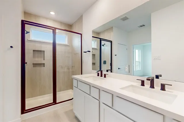 a bathroom with a double vanity sink mirror and shower