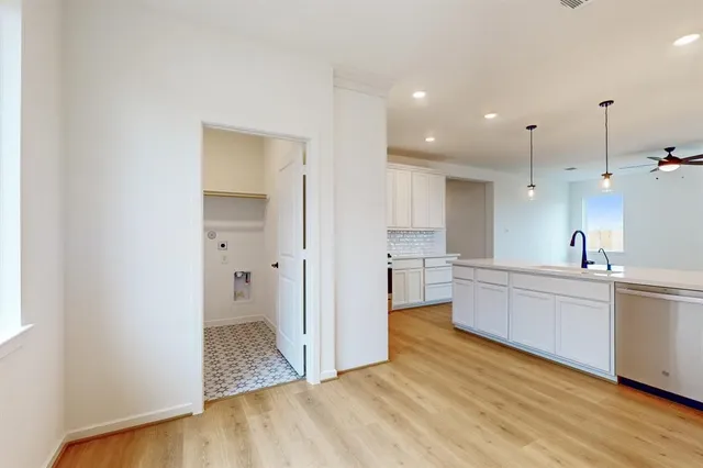 a large white kitchen with a sink and dishwasher a refrigerator with wooden floor