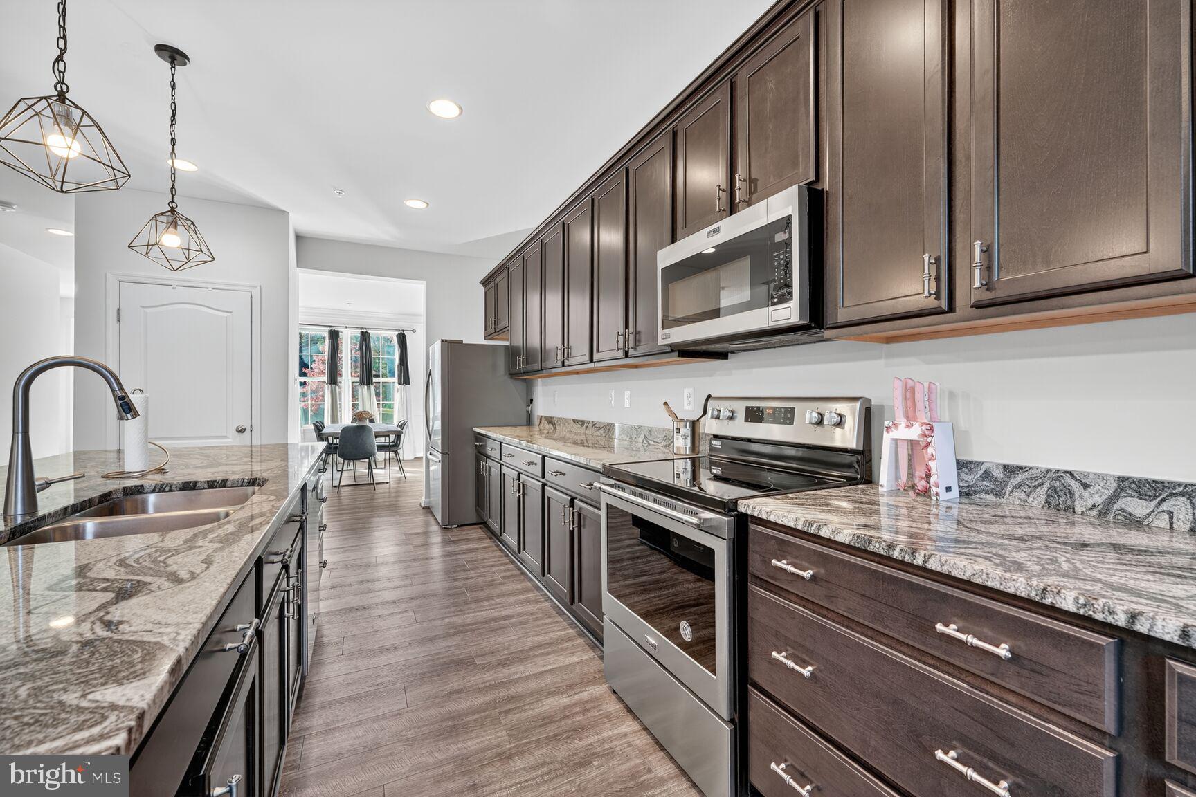 711 Yarrow Court Accokeek, MD 20607 - Photo 13 of 40 a kitchen with stainless steel appliances granite countertop a stove a sink dishwasher and a microwave oven with wooden cabinets