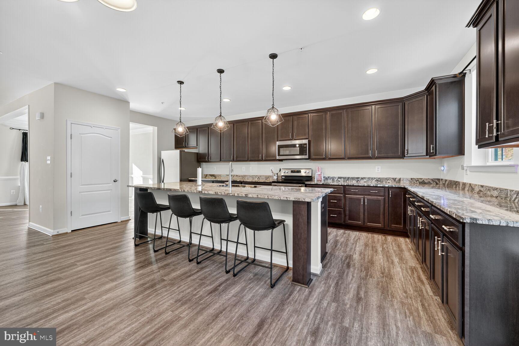 711 Yarrow Court Accokeek, MD 20607 - Photo 9 of 40 a kitchen with stainless steel appliances kitchen island granite countertop a stove a sink dishwasher a refrigerator and a dining table with wooden floor