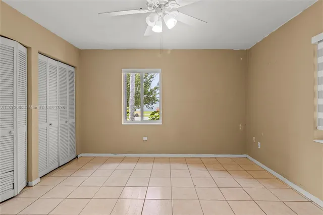 a view of an empty room with window and chandelier fan