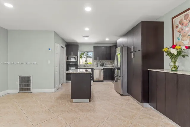 a kitchen with stainless steel appliances kitchen island granite countertop refrigerator and cabinets