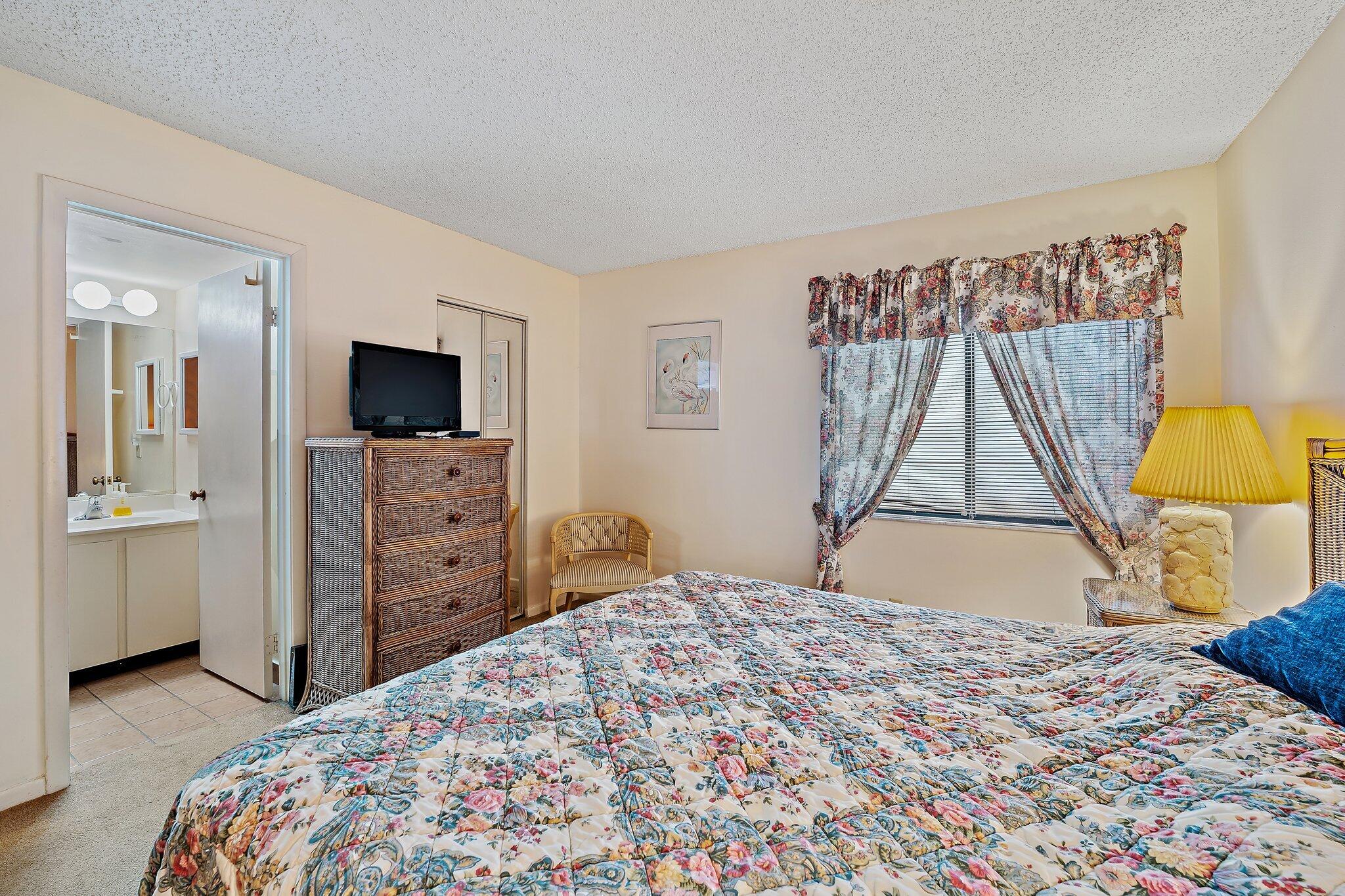 1605 Highway 1, Unit B104 Jupiter, FL 33477 - Photo 17 of 24 a bedroom with a bed and a flat tv screen on dresser
