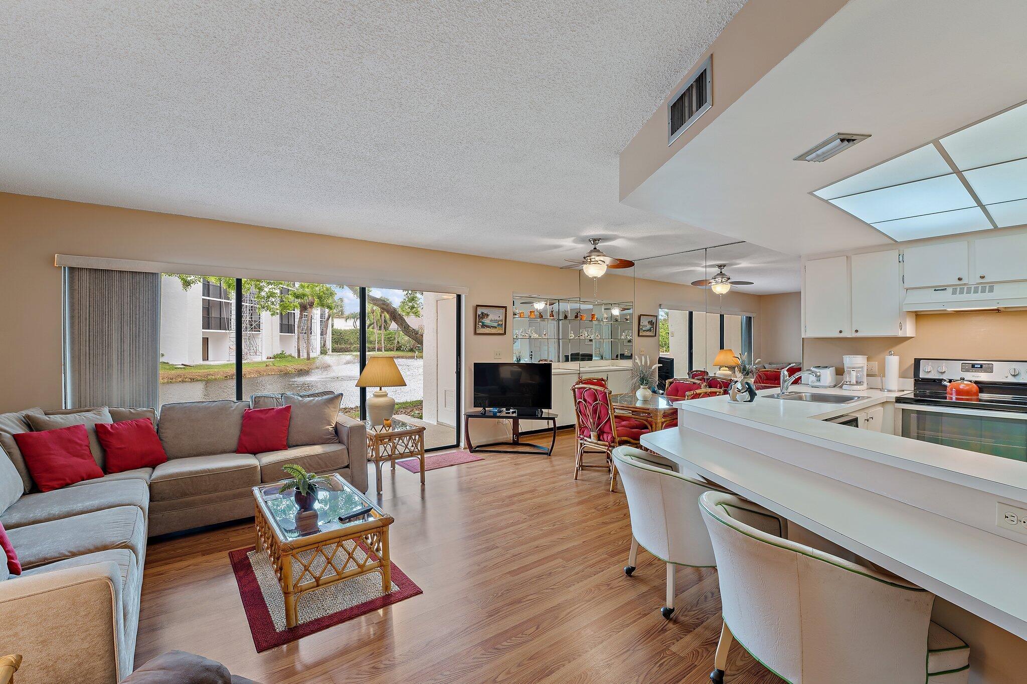 1605 Highway 1, Unit B104 Jupiter, FL 33477 - Photo 4 of 24 a living room with furniture a flat screen tv and a floor to ceiling window