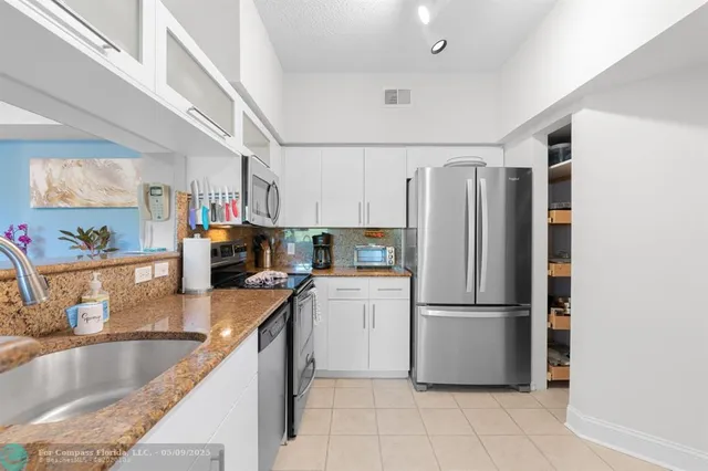 a kitchen with granite countertop a refrigerator and a sink