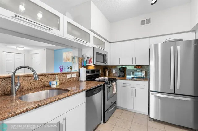 a kitchen with stainless steel appliances granite countertop a sink refrigerator and cabinets