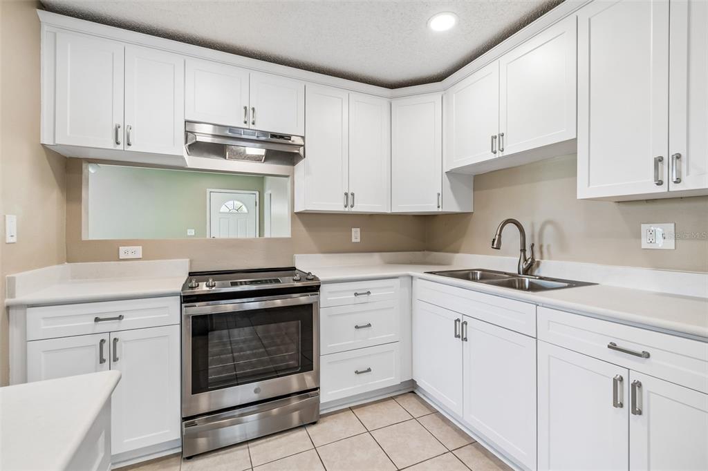 209 Genet Court Sun City Center, FL 33573 - Photo 11 of 31 a kitchen with granite countertop white cabinets and stainless steel appliances