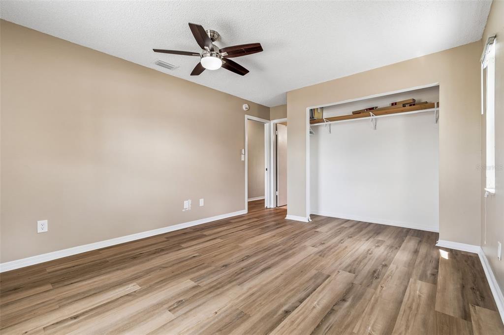 209 Genet Court Sun City Center, FL 33573 - Photo 18 of 31 a view of an empty room with wooden floor and a ceiling fan