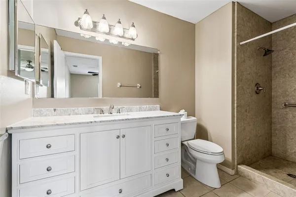 a bathroom with a granite countertop sink a toilet and a mirror