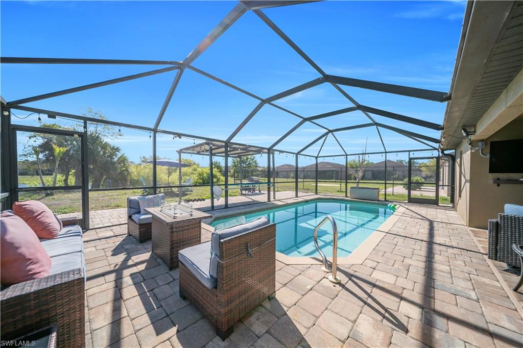 175 Shadowview Court Lehigh Acres, FL 33974 - Photo 8 of 39 Outdoor pool with a sunroom, a patio, glass enclosure, and an outdoor hangout area