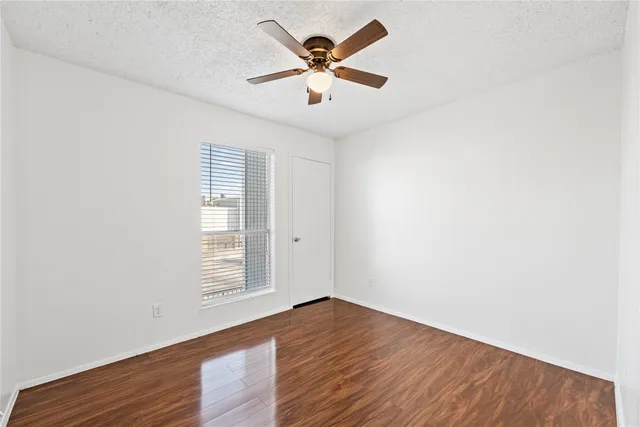 an empty room with wooden floor and ceiling fan