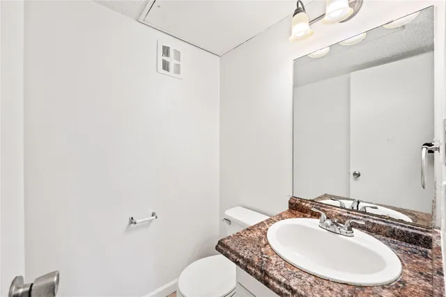 a bathroom with a granite countertop sink a mirror and a toilet