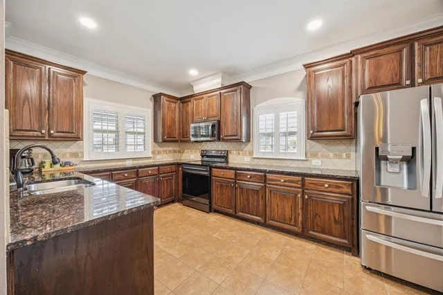a kitchen with stainless steel appliances granite countertop a refrigerator stove top oven and sink