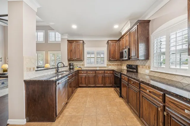 a large kitchen with stainless steel appliances granite countertop wooden cabinets a sink and a stove