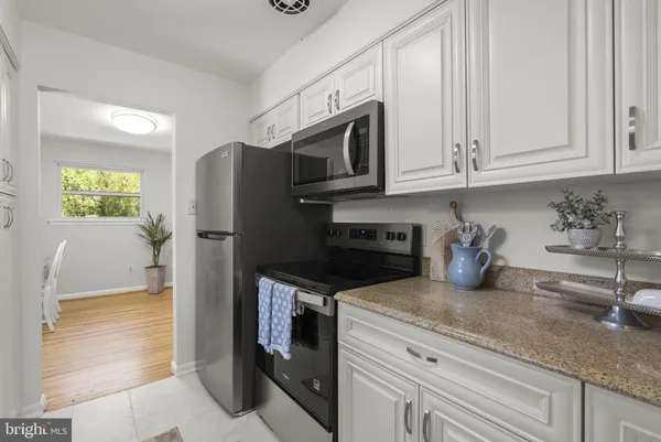 a kitchen with granite countertop white cabinets and stainless steel appliances