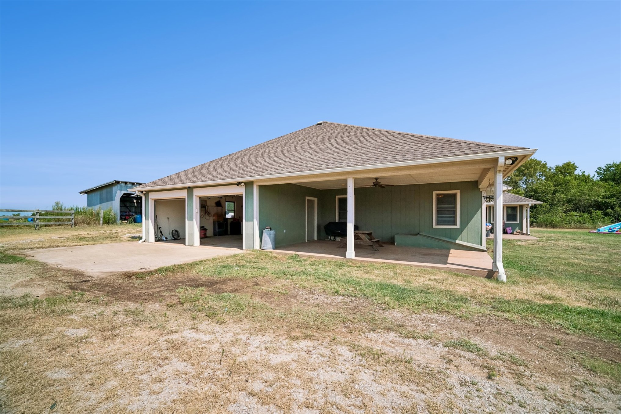 49301 South 360 Road Pawnee, OK 74058 - Photo 32 of 44 Green exterior siding with a covered patio, two-car garage, and an additional detached structure