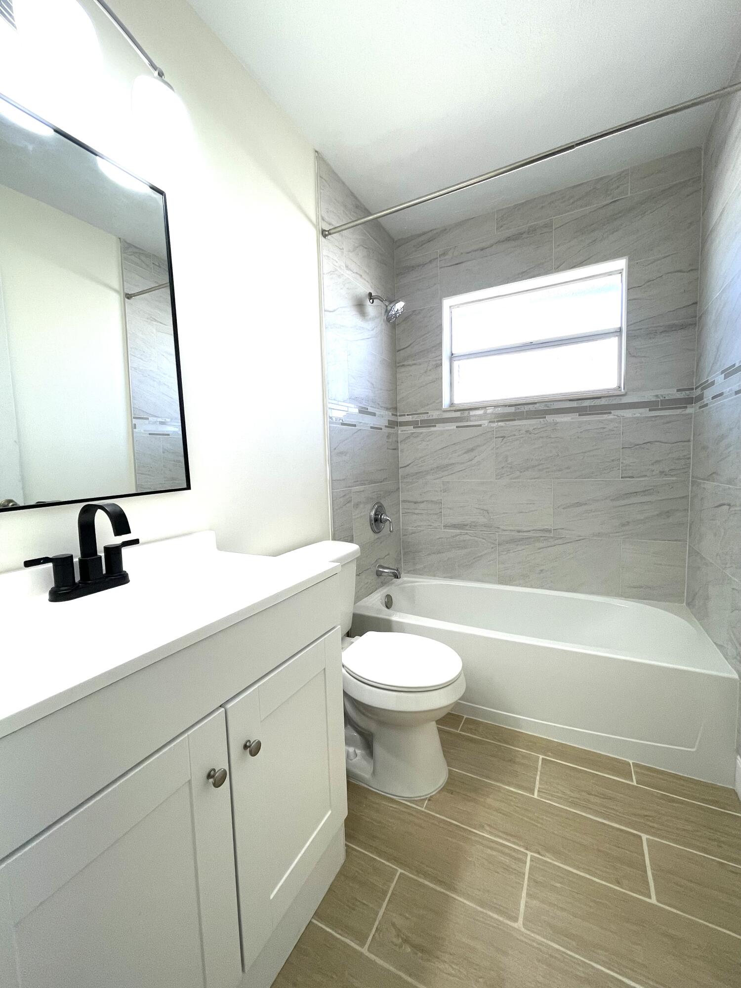 5753 Southeast Mercedes Avenue Stuart, FL 34997 - Photo 11 of 24 a bathroom with a toilet a sink a mirror and bathtub