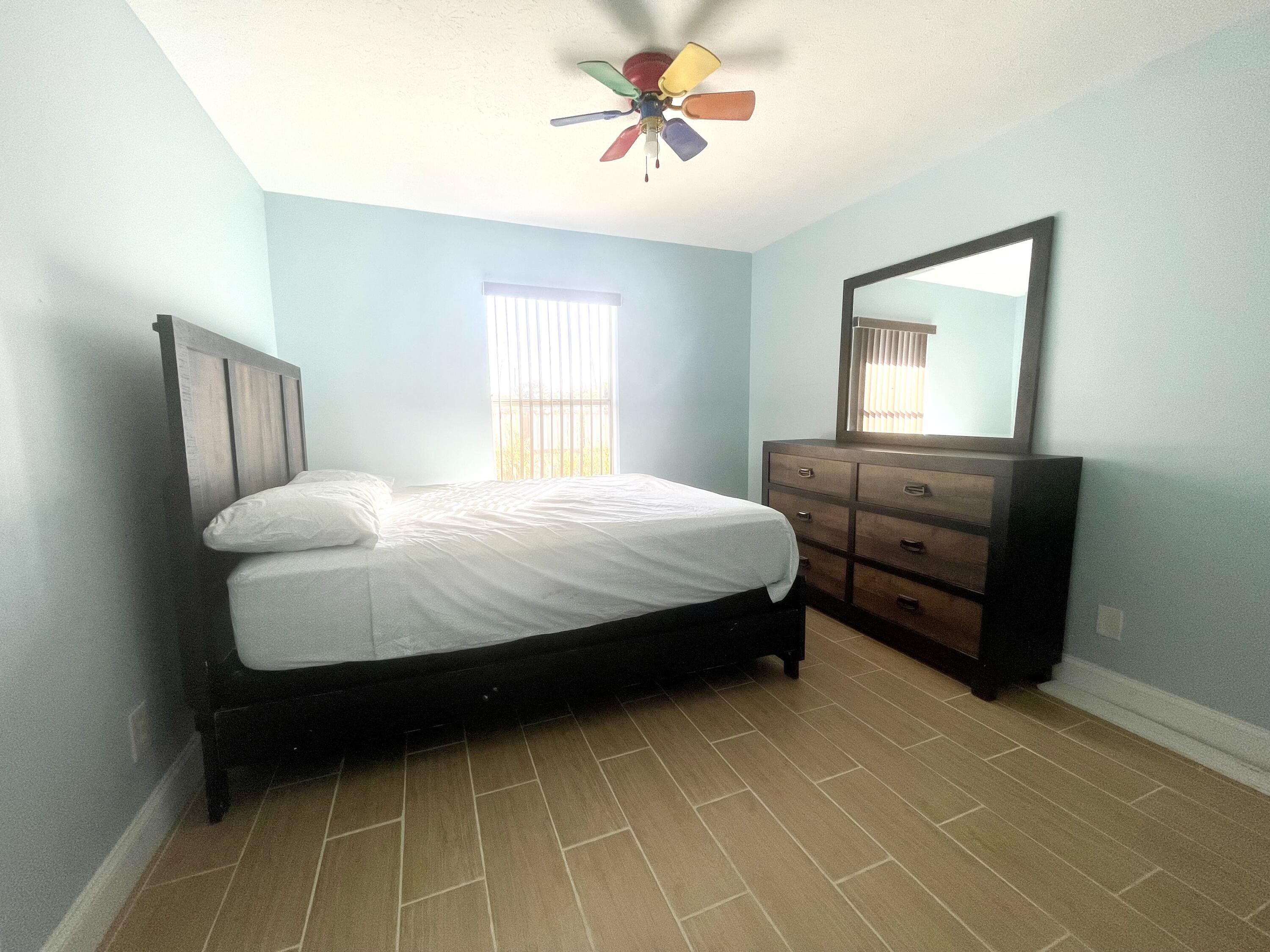5753 Southeast Mercedes Avenue Stuart, FL 34997 - Photo 18 of 24 a bedroom with a bed and a chandelier fan