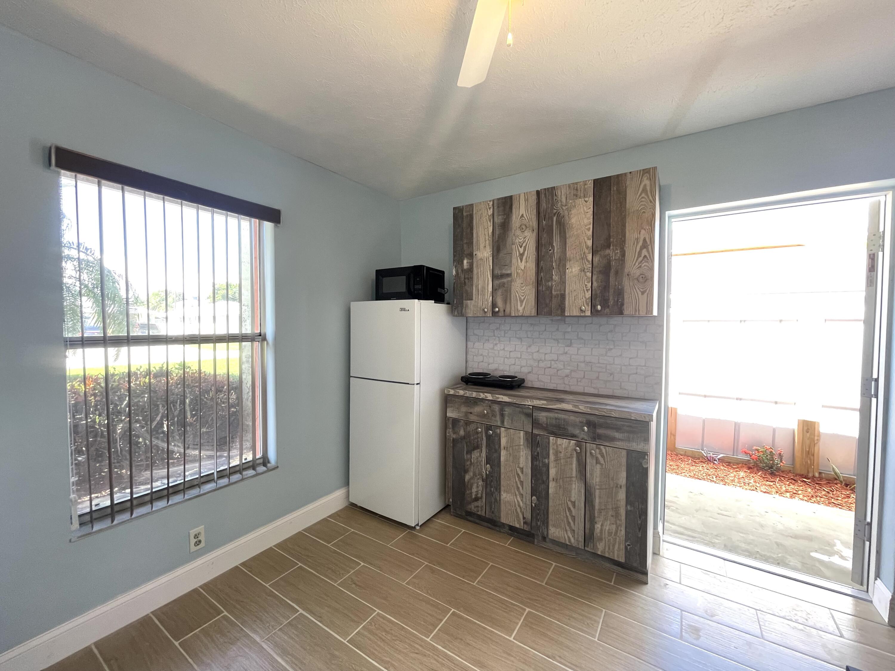 5753 Southeast Mercedes Avenue Stuart, FL 34997 - Photo 7 of 24 a kitchen with a refrigerator a washer dryer and white cabinets
