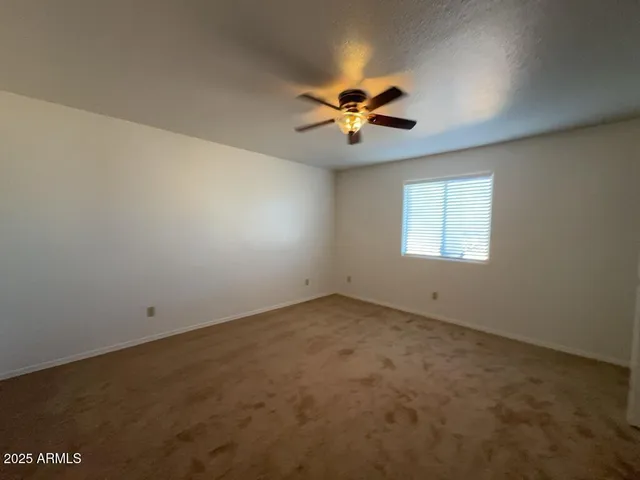 an empty room with windows and ceiling fan