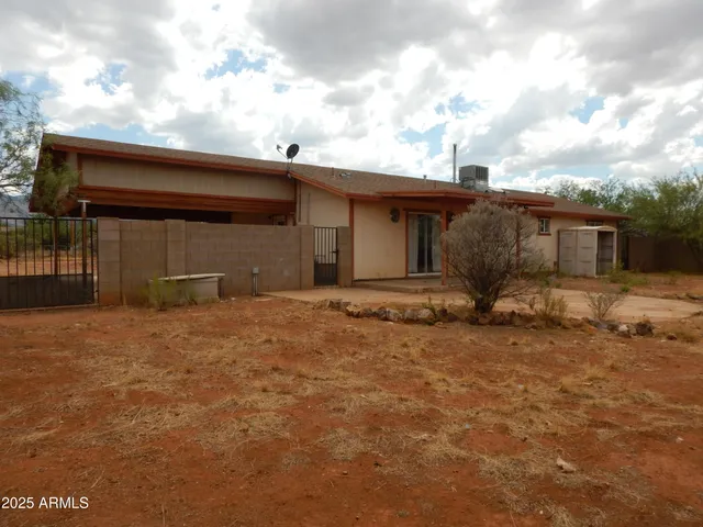 a backyard of a house with wooden fence and a barbeque