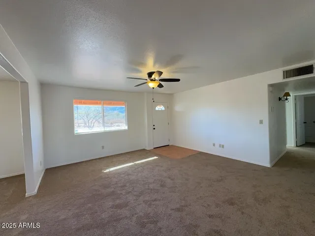 an empty room with windows and fan
