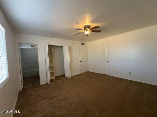 an empty room with a bathroom and a ceiling fan
