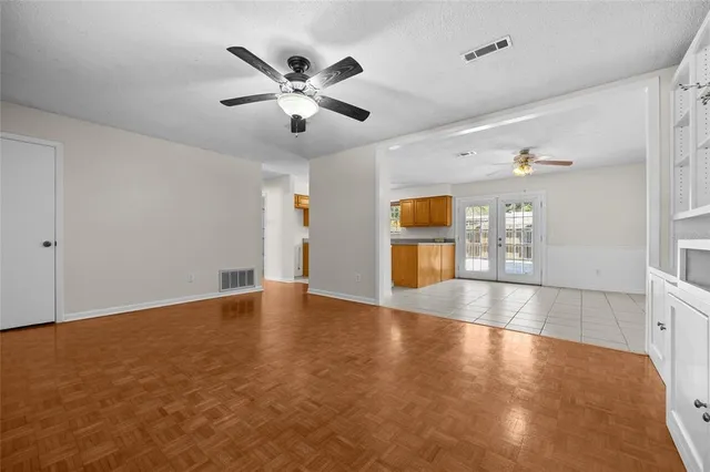 a view of an empty room with window and wooden floor