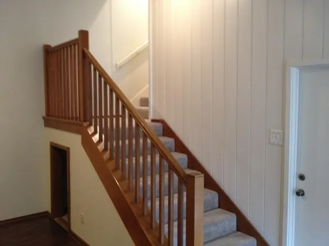 a view of staircase with railing and white walls