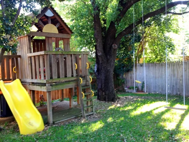 a view of backyard with deck and a slide