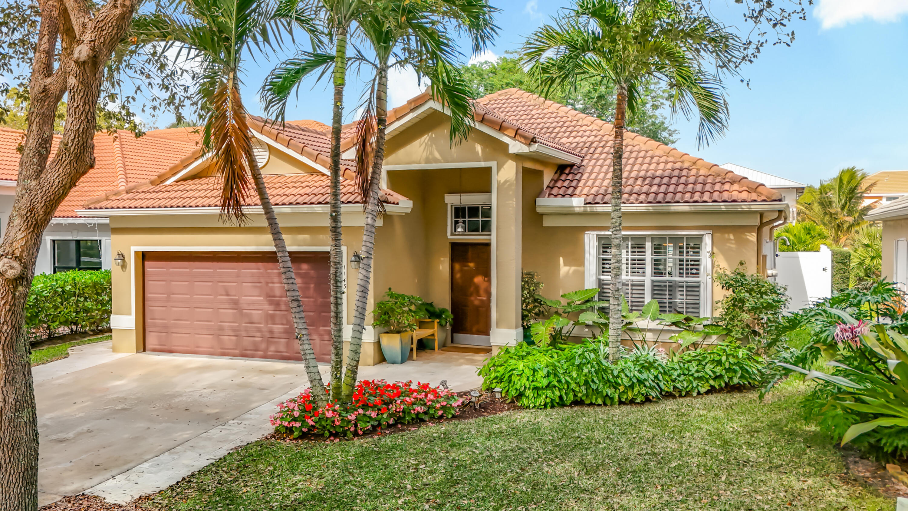front view of a house with a yard and palm trees