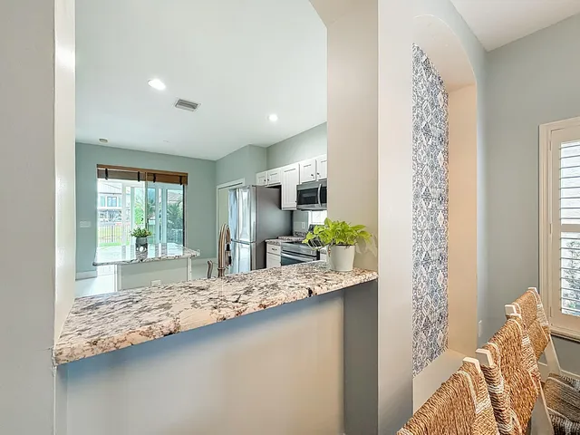 a kitchen with granite countertop kitchen island stainless steel appliances a stove sink and refrigerator