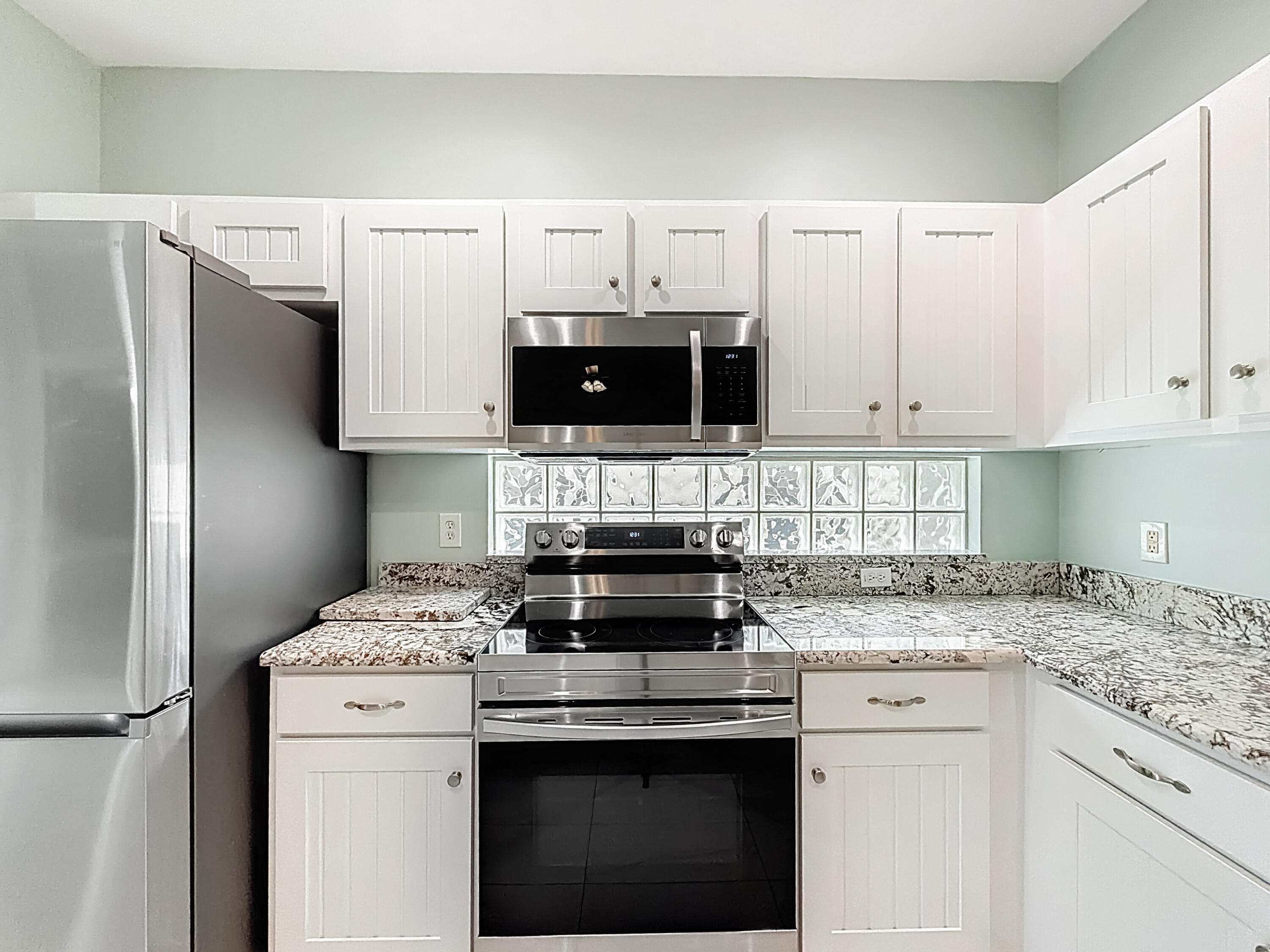 1143 Canoe Point Delray Beach, FL 33444 - Photo 29 of 85 a kitchen with stainless steel appliances granite countertop a stove a sink and a refrigerator