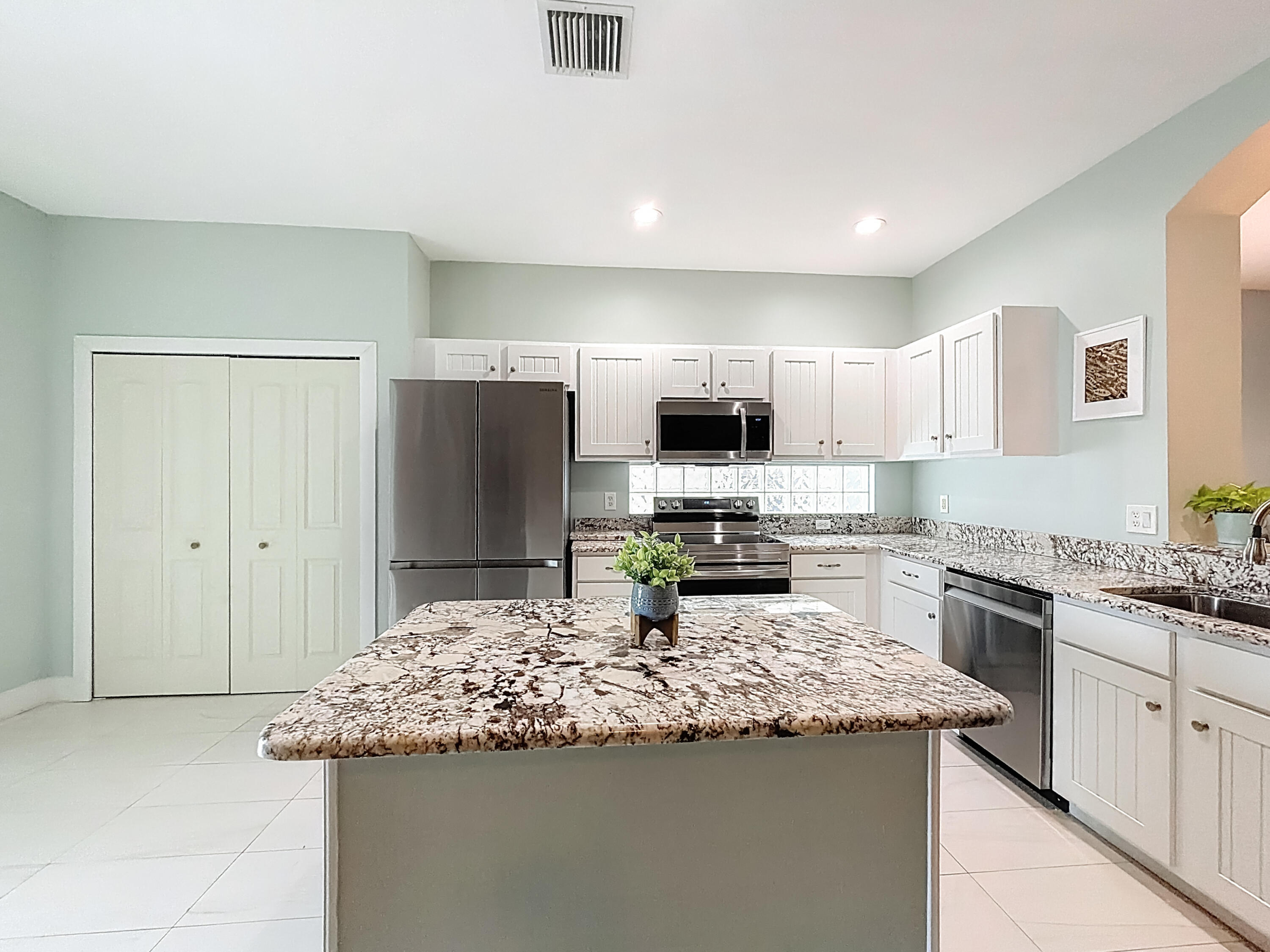 1143 Canoe Point Delray Beach, FL 33444 - Photo 31 of 85 a kitchen with kitchen island granite countertop a sink stove and refrigerator