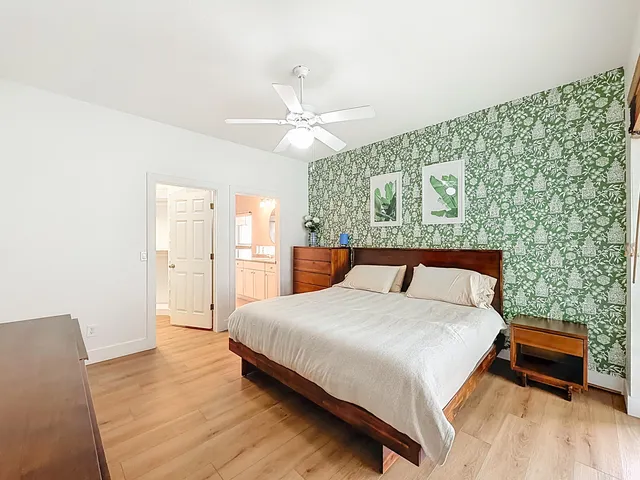 an empty room with wooden floor chandelier fan and windows