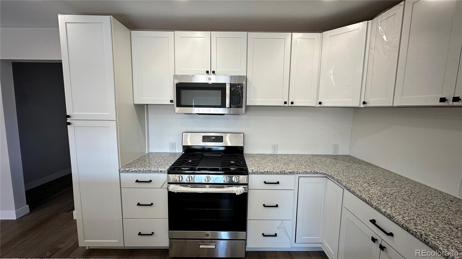 215 6th Street Hugo, CO 80821 - Photo 11 of 28 a kitchen with stainless steel appliances granite countertop white cabinets a stove a sink and dishwasher