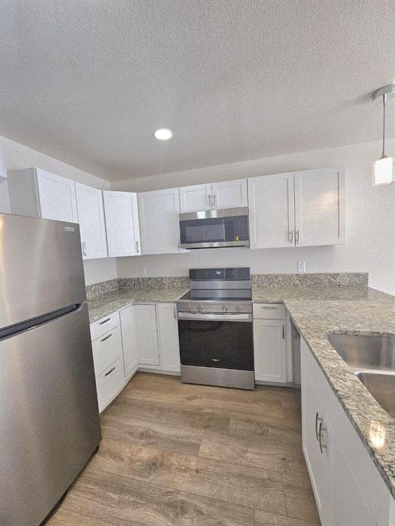a kitchen with granite countertop cabinets appliances and a sink