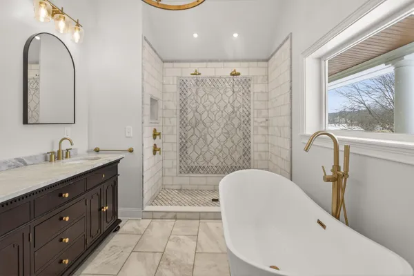 a bathroom with a double vanity sink a mirror a window and a bathtub