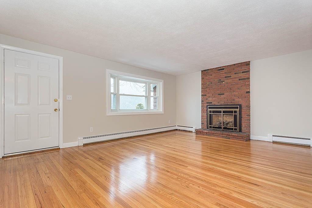 25 Garland Road Chelmsford, MA 01824 - Photo 2 of 25 an empty room with wooden floor fireplace and windows