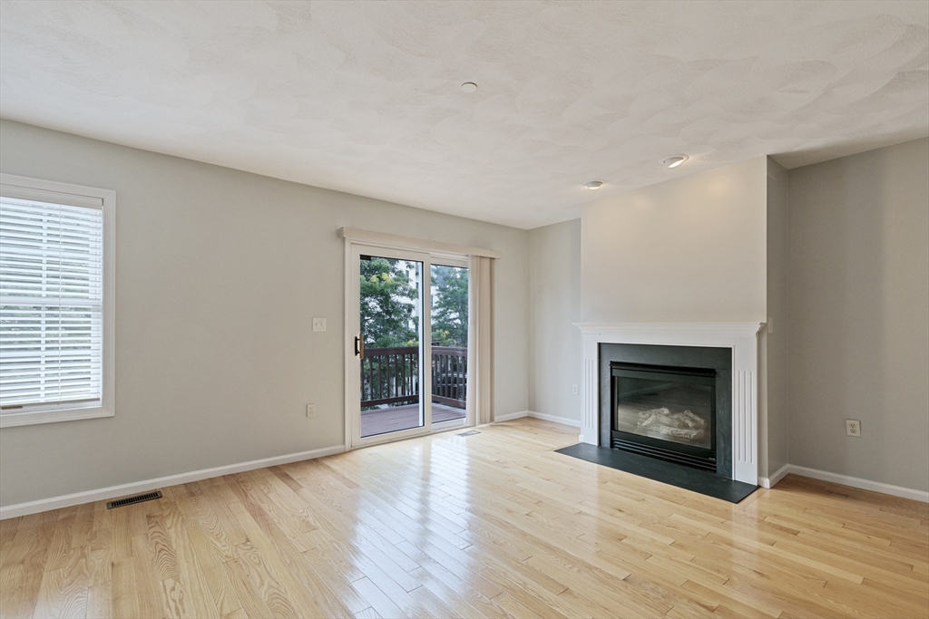 555 Main Street, Unit 10 Woburn, MA 01801 - Photo 16 of 39 an empty room with wooden floor fireplace and windows