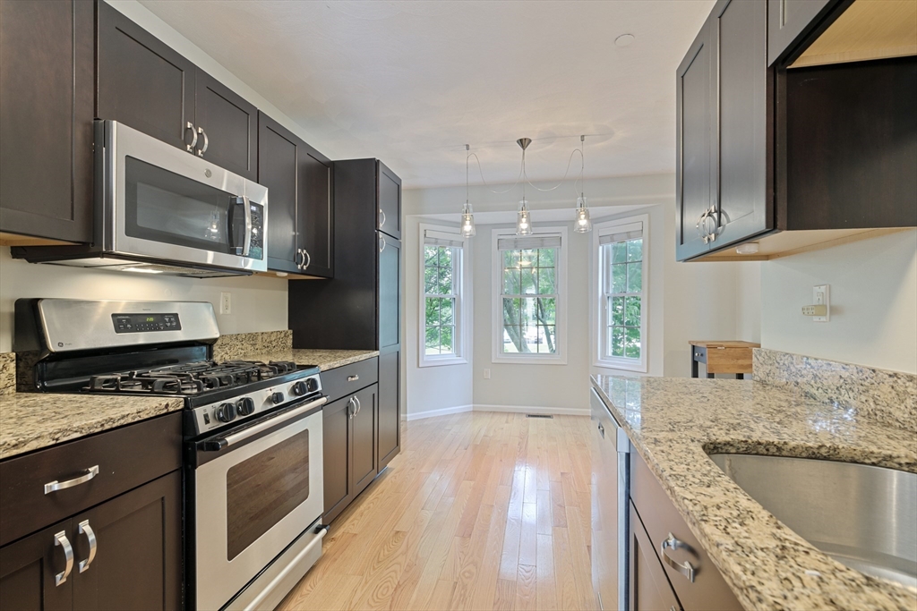 555 Main Street, Unit 10 Woburn, MA 01801 - Photo 8 of 39 a kitchen with granite countertop wooden cabinets stainless steel appliances and a counter space