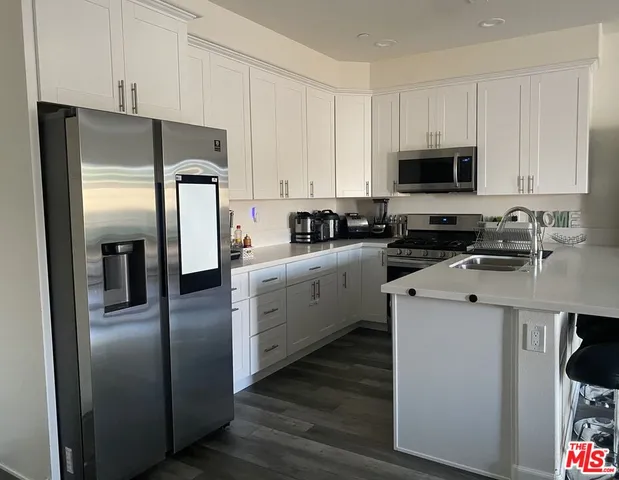 a kitchen with stainless steel appliances a refrigerator sink and white cabinets