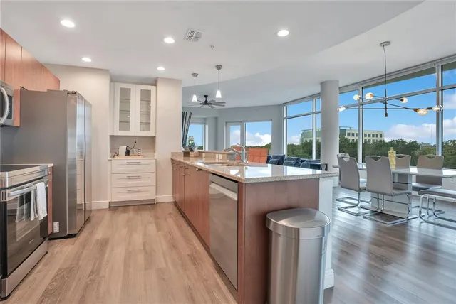 a kitchen with stainless steel appliances kitchen island granite countertop a refrigerator a stove and a sink with wooden floor