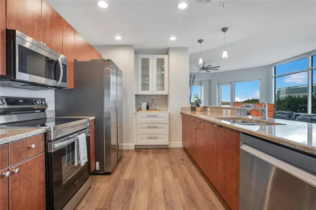 a kitchen with stainless steel appliances granite countertop a refrigerator oven a sink dishwasher and white cabinets with wooden floor