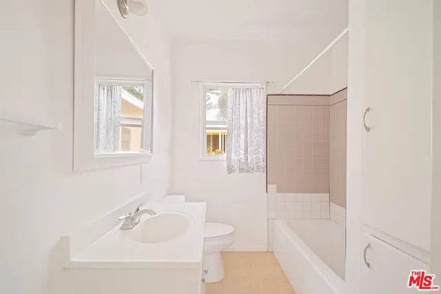 a bathroom with a tub shower sink vanity and toilet