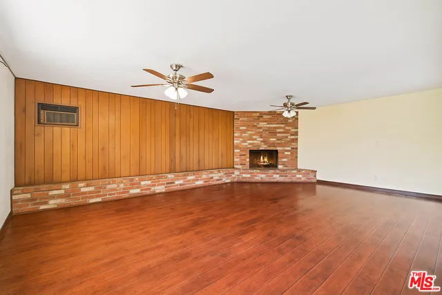 an empty room with a fireplace and wooden floor
