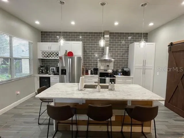 a kitchen with stainless steel appliances granite countertop a dining table chairs refrigerator and microwave