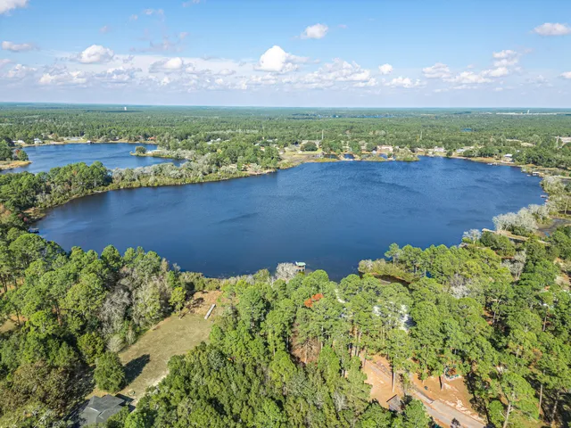 an aerial view of ocean with residential house and lake in the background