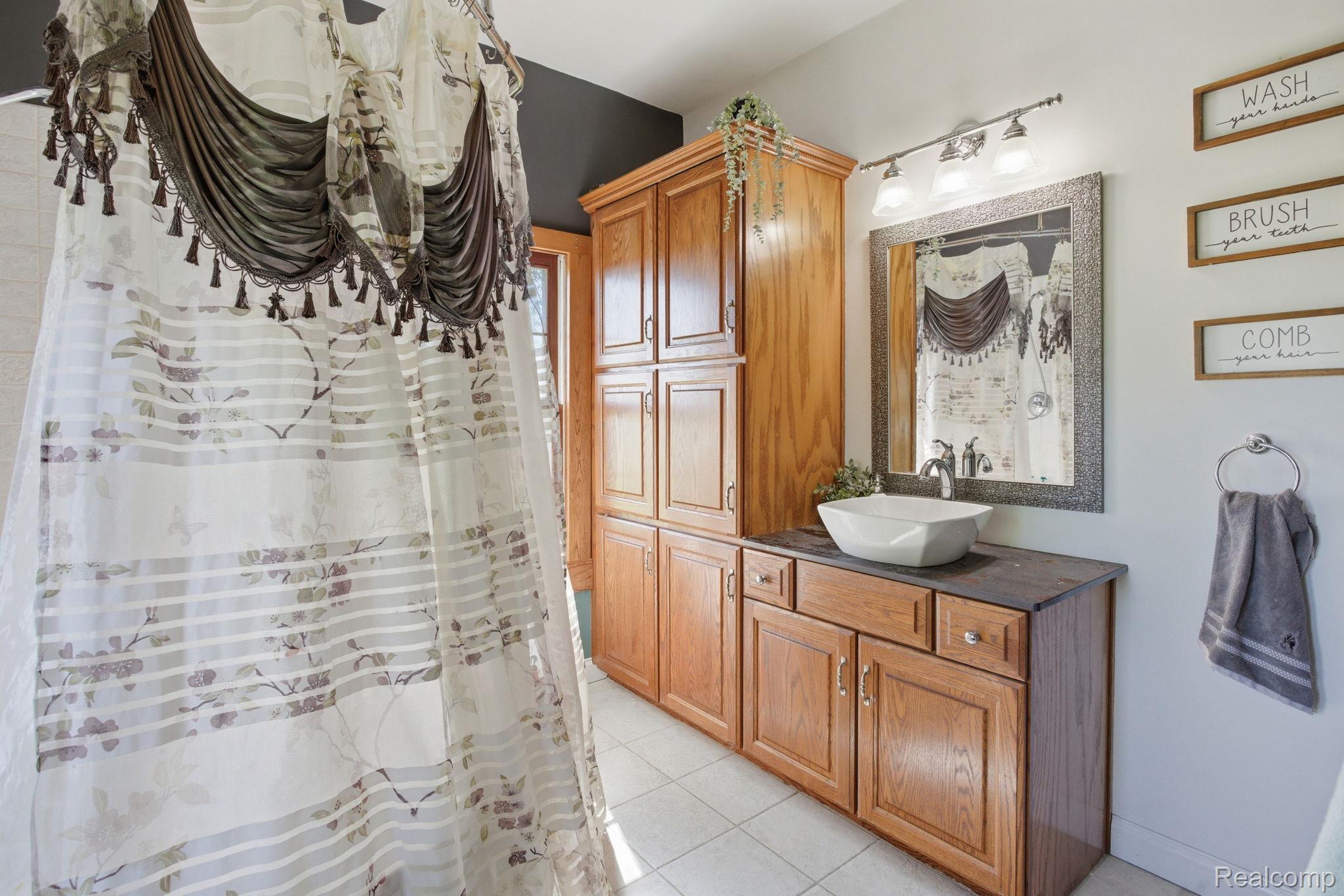 14104 Carleton West Road Carleton, MI 48117 - Photo 24 of 58 Bathroom featuring a shower with shower curtain, vanity, and light tile patterned floors